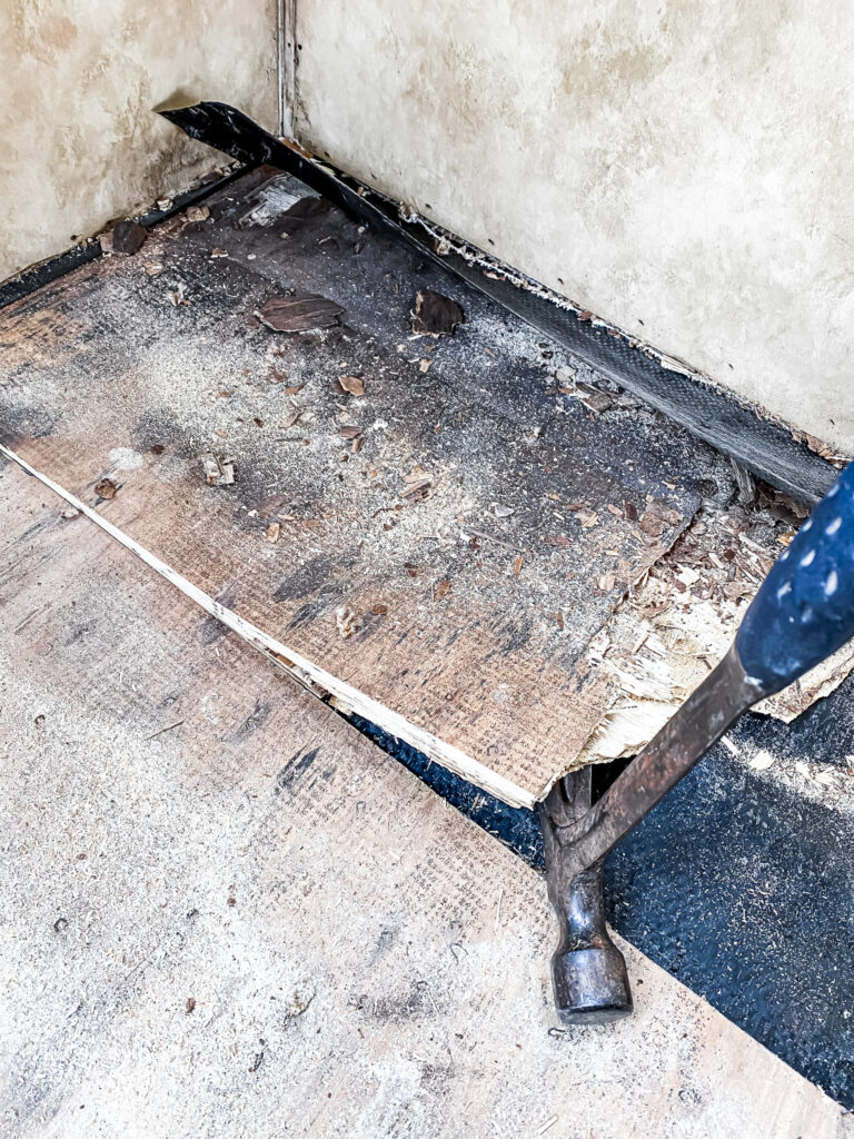 Hammer prying off plywood of RV slide out with water damaged floors